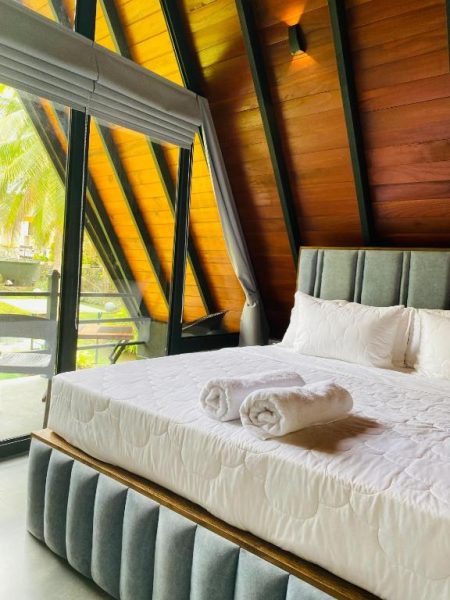 Habitación tipo cabaña con techo de madera y cama doble con vistas al jardín en Avinka Grand