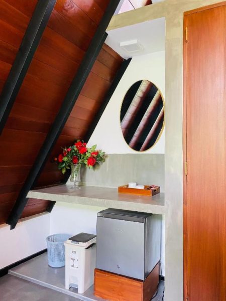 Habitación con escritorio de concreto, minibar y flores rojas en Hotel Avinka Grand
