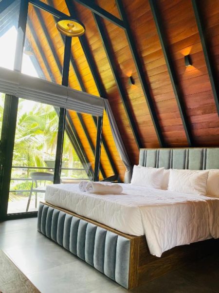 Habitación de lujo con techo de madera y cama doble con vista tropical en Avinka Grand