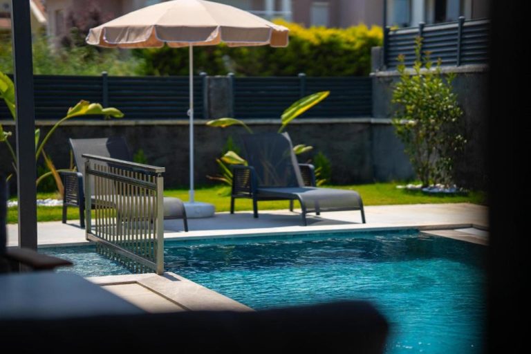 Piscina exterior con tumbonas y sombrilla en las Villas Zora Beyaz Taş, zona de relax