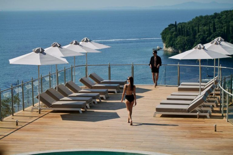 Terraza con tumbonas y sombrillas blancas con vistas al mar en San Antonio Corfu Resort Adults Only