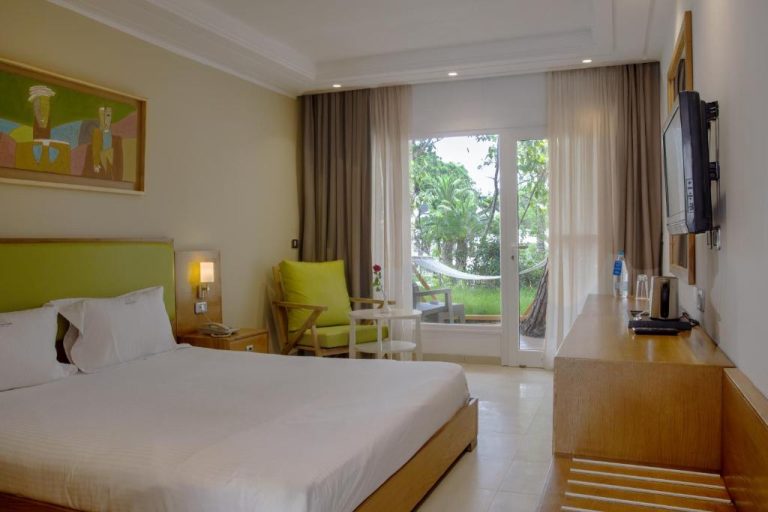 Habitación doble con cama king, cabecero verde y vistas al jardín en Hotel Bel Azur Thalasso