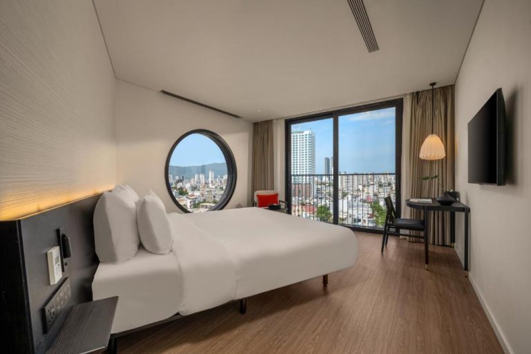 Habitación doble con cama king, ventana circular y vistas panorámicas de la ciudad en Caro Premium Danang Hotel