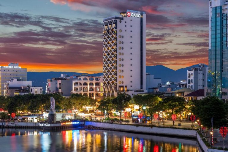 Vista nocturna del Caro Premium Danang Hotel junto al río con espectacular atardecer en Da Nang