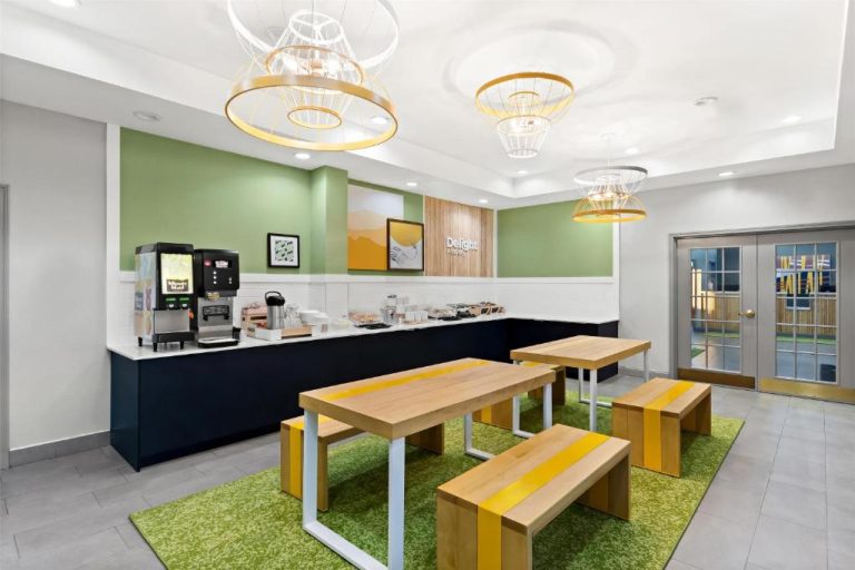 Zona de desayuno buffet con mesas y bancos de madera en Spark by Hilton Panama City Beach