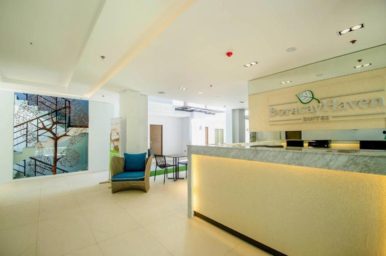 Recepción moderna e iluminada del Boracay Haven Suites con mostrador de mármol y zona de espera