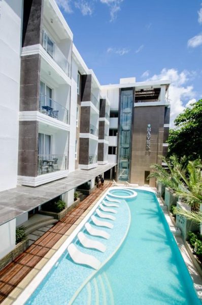Piscina exterior alargada con tumbonas del Boracay Haven Suites rodeada de balcones y vegetación tropical