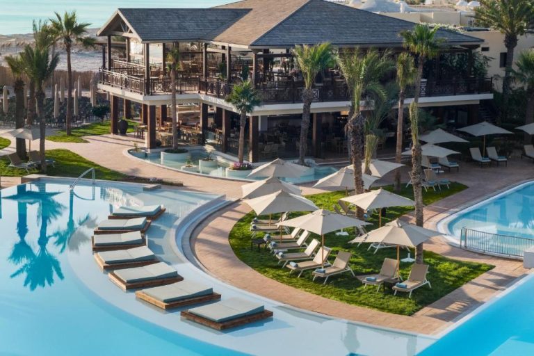 Piscina exterior con tumbonas flotantes y restaurante del Iberostar Selection Eolia Djerba