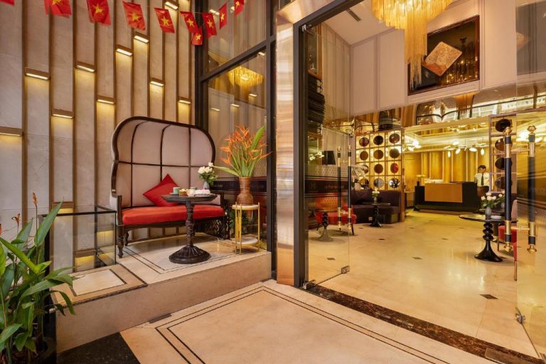 Elegante lobby con decoración colonial vietnamita y recepción dorada en Le Premier Hotel & Rooftop Bar