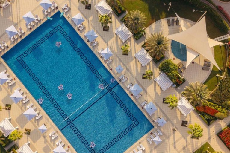 Vista aérea de la piscina exterior con tumbonas y sombrillas del The St. Regis Doha