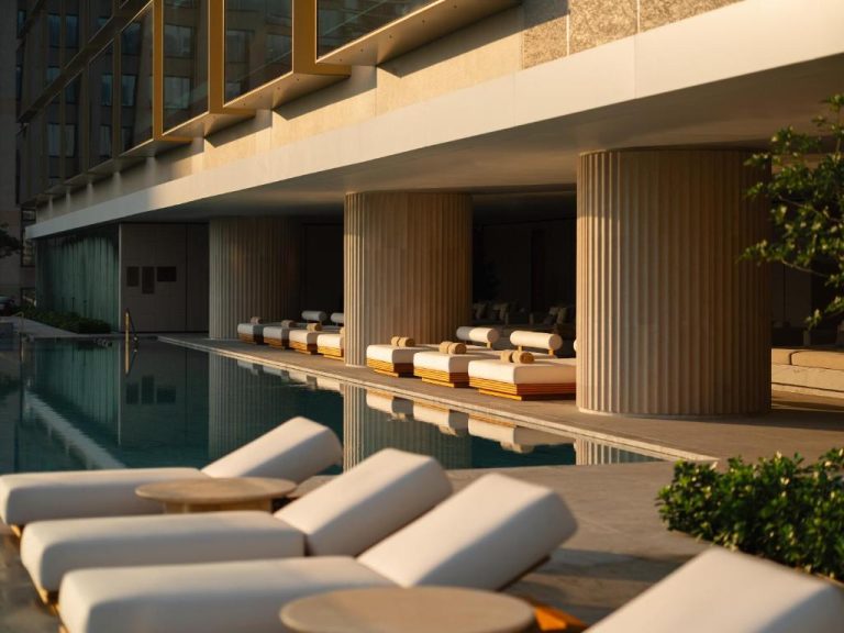 Piscina exterior con tumbonas de lujo y columnas elegantes del hotel Dusit Thani Bangkok al atardecer