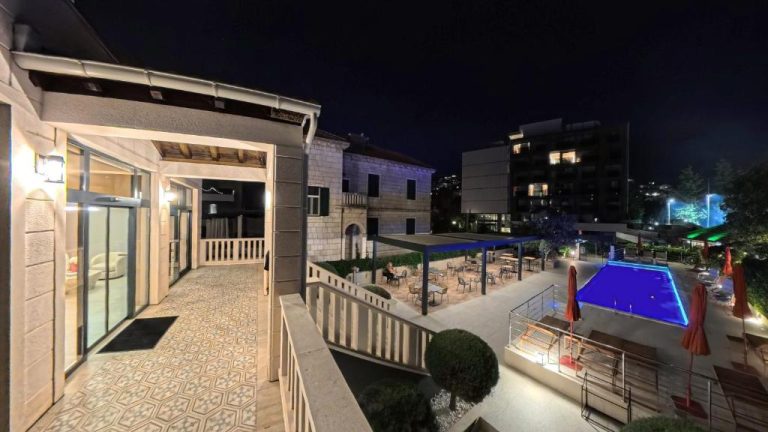 Piscina exterior iluminada de noche en el Hotel Aquarius Dubrovnik con terraza y zona de descanso