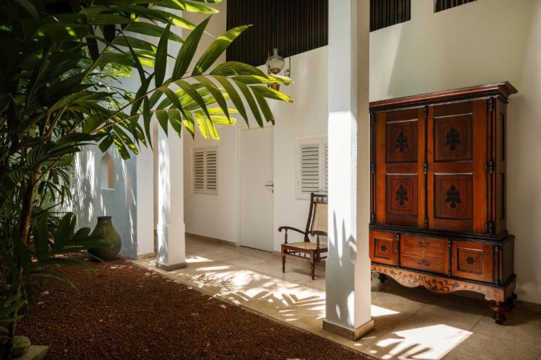 Patio interior colonial con armario de madera antiguo y vegetación tropical en Jetwing Ratnam Residence