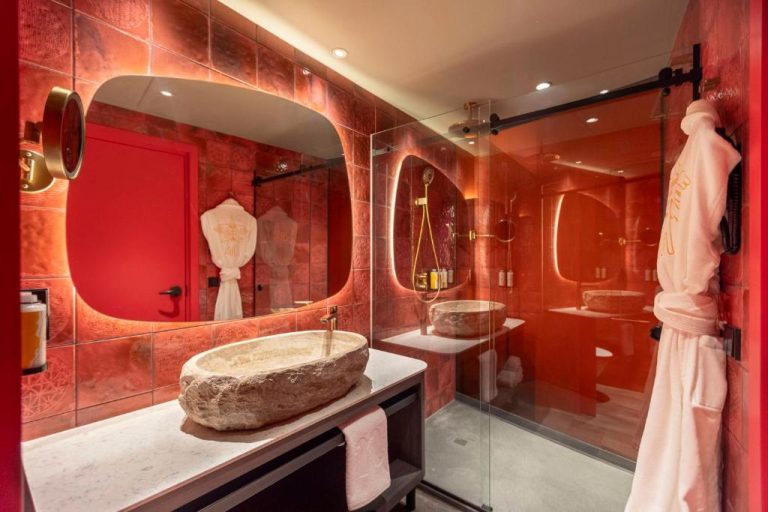 Baño de diseño en rojo con lavabo de piedra natural y ducha en el hotel Nhow Lima