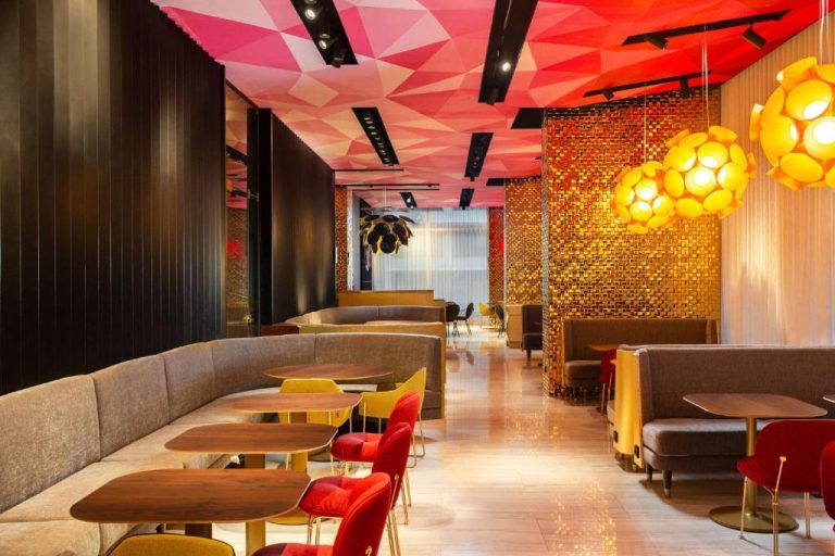 Bar lounge del Nhow Lima con techo geométrico rosa, paredes doradas y colorido mobiliario moderno