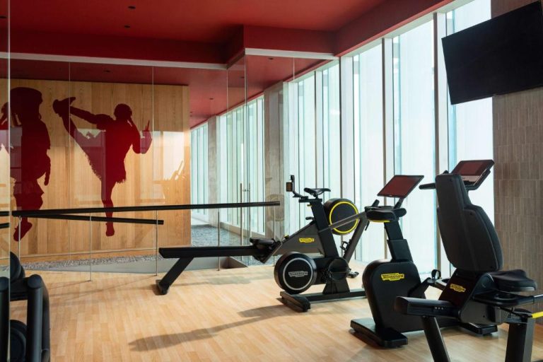 Gimnasio moderno con bicicletas estáticas Technogym y decoración en rojo del hotel Nhow Lima
