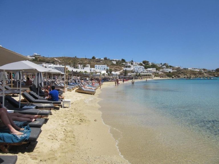 Playa de arena dorada con tumbonas y sombrillas del Acrogiali Beachfront Hotel Mykonos