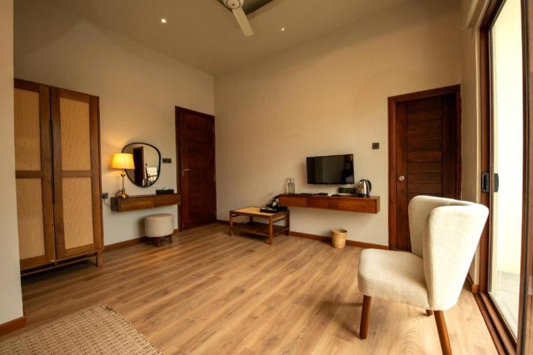 Habitación con salón, suelo de madera, televisión y silla en Kevans Casa