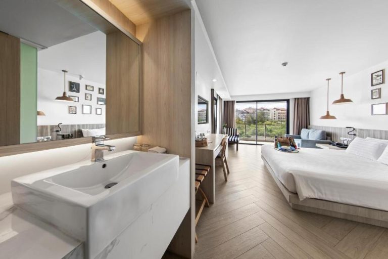 Habitación deluxe con baño abierto y cama doble con vistas al balcón en Golden Tulip Pattaya Beachfront Resort