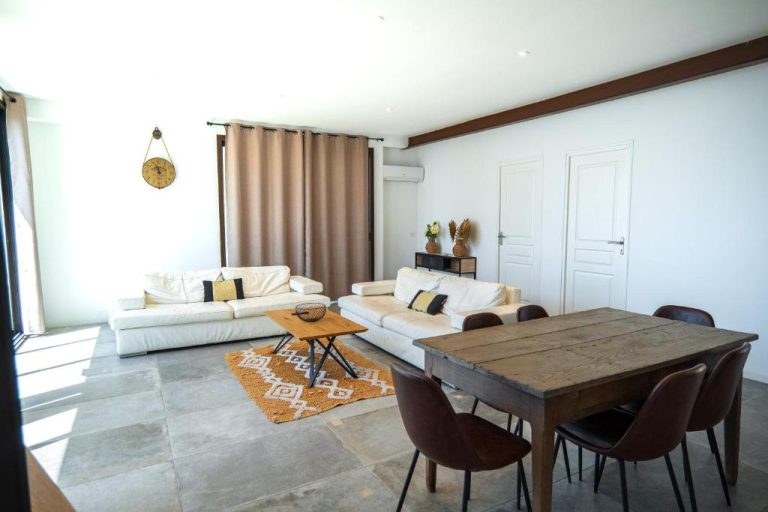 Salón comedor luminoso con sofás blancos y mesa de madera rústica en Hotel L'Escale