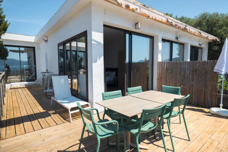 Terraza exterior con mesa y sillas verdes del Hotel L'Escale con vistas al mar y acceso directo a la habitación