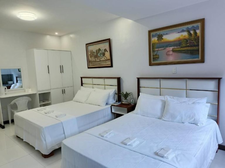 Habitación doble con dos camas blancas y cuadros decorativos en EPM Tower Hotel and Events Place