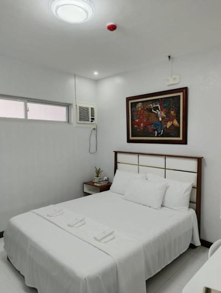 Habitación doble con cama matrimonial blanca y aire acondicionado en EPM Tower Hotel and Events Place
