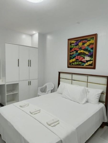 Habitación doble con cama matrimonial blanca y cuadro colorido en EPM Tower Hotel and Events Place