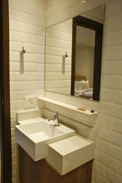 Baño moderno con lavabo cuadrado y espejo del Hotel Urban L con azulejos blancos