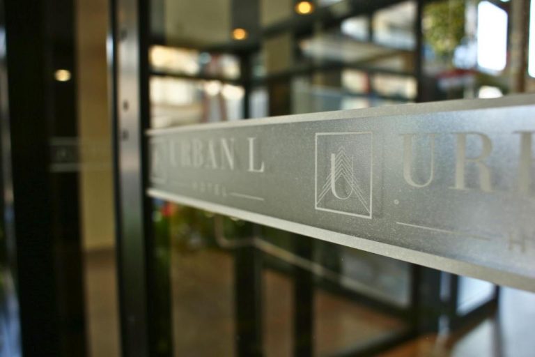 Entrada principal con puerta de cristal grabado del Hotel Urban L con logo elegante