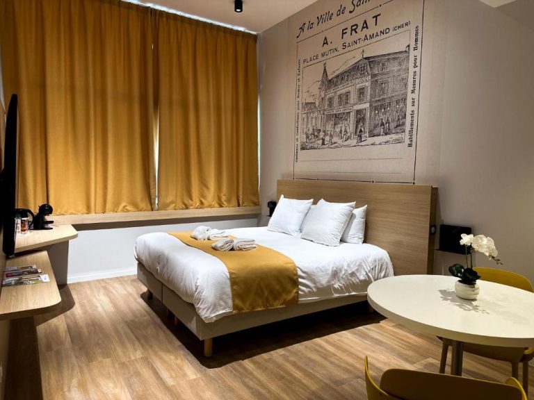 Habitación doble con decoración vintage y cartel histórico de A. Frat en el Hotel Le Noirlac