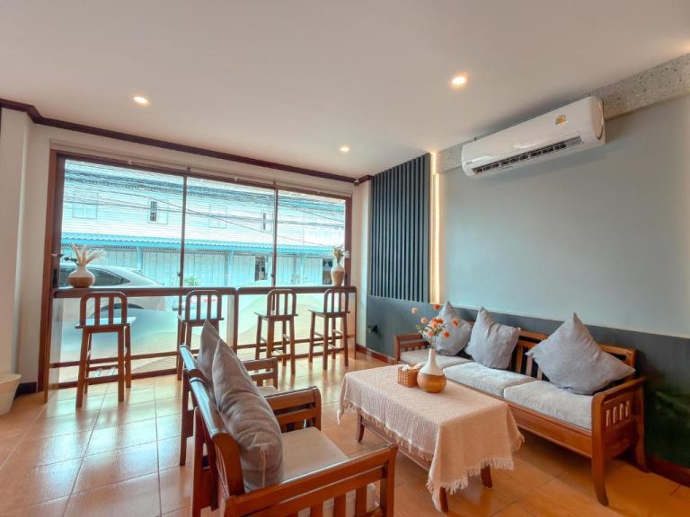Sala de estar con sofás de madera y vistas al exterior en ClayHouse Samui Boutique Hotel