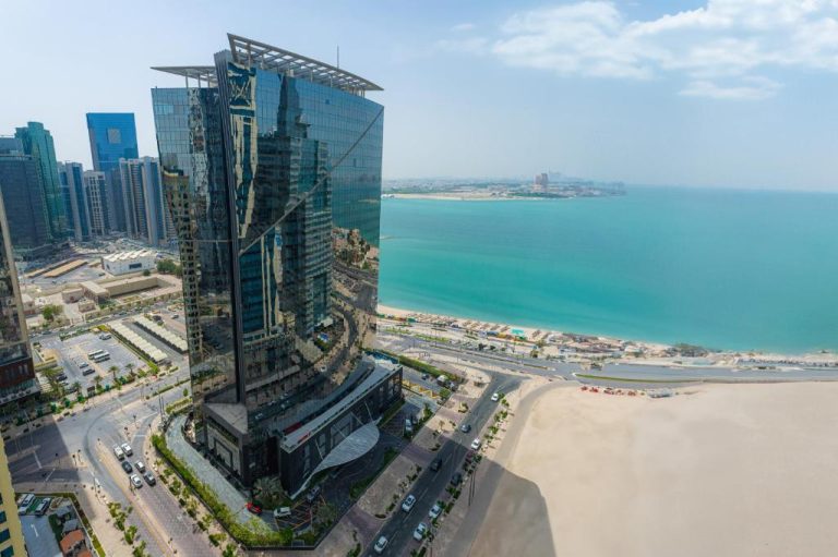 Vista aérea del W Doha con su torre de cristal junto a la playa y el mar turquesa de Qatar