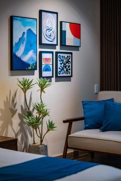 Habitación elegante con galería de cuadros artísticos y sillón azul en Anise Luxe Home