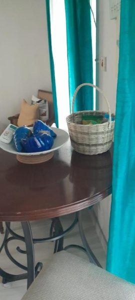 Mesa de madera con decoración en azul y cesta tejida en sala de Deluxe SandCastles Condos
