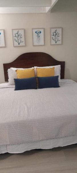 Habitación con cama doble y almohadas azules y amarillas en Deluxe SandCastles Condos