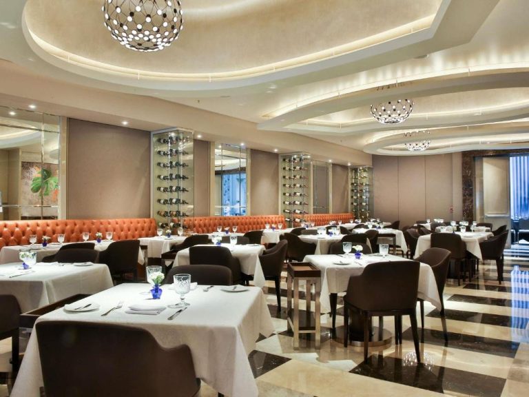 Elegante restaurante del Palladio Hotel Buenos Aires MGallery con mesas vestidas y bodega integrada