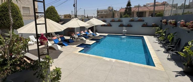Piscina exterior con tumbonas y sombrillas del Grand Hotel Madaba en Jordania
