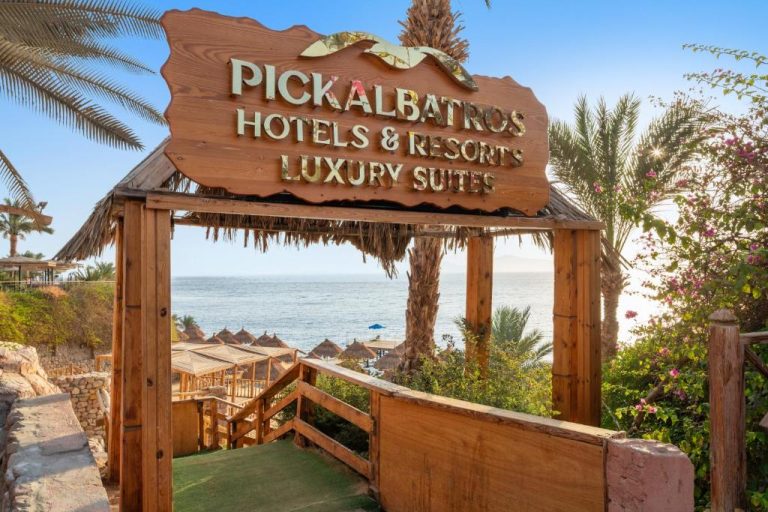 Entrada de madera con cartel del Pickalbatros Golf Luxury Suites con vistas al mar y palmeras