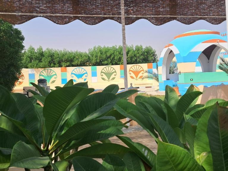 Jardín exterior con mural decorativo de motivos egipcios y cúpula azul del Aton Palace Luxor
