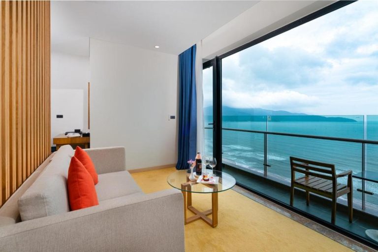Habitación con sofá y balcón con vistas panorámicas al mar en Sala Danang Beach Hotel
