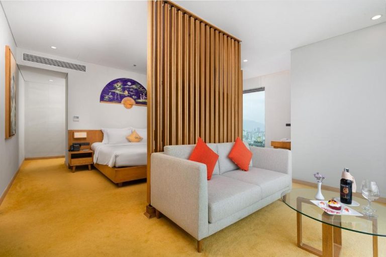 Suite con salón y separador de madera estilo japonés en Sala Danang Beach Hotel con vistas a la ciudad