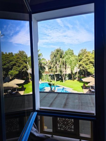 Vista desde habitación a la piscina exterior rodeada de jardines y palmeras del Hotel Anna Agadir