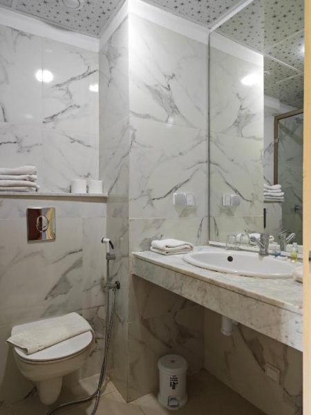 Baño de mármol blanco con lavabo y ducha teléfono en el Hotel Anna Agadir