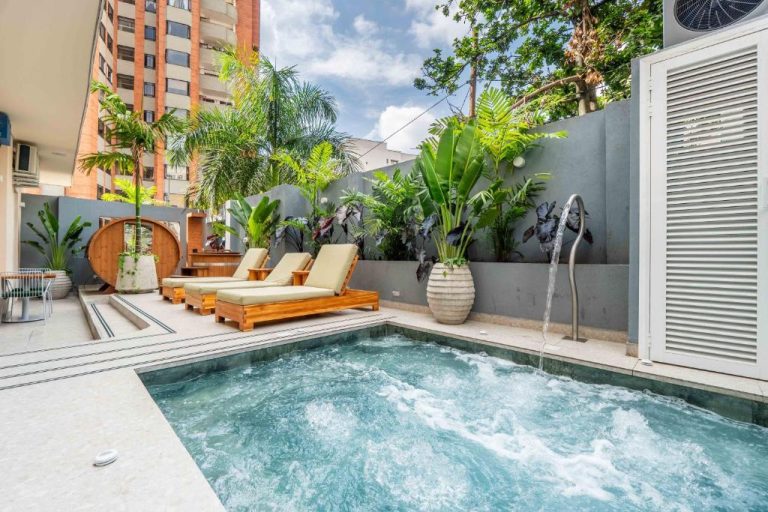 Piscina con jacuzzi y tumbonas en zona exterior tropical del Veca Flats Centenario