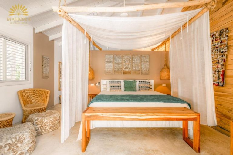 Habitación con cama dosel de madera y cortinas blancas en Mahona Boutique Hotel