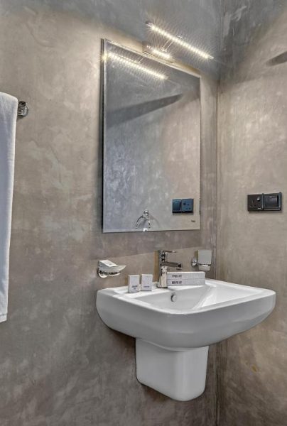 Baño moderno con lavabo blanco y espejo iluminado en The Tusker's Hideout