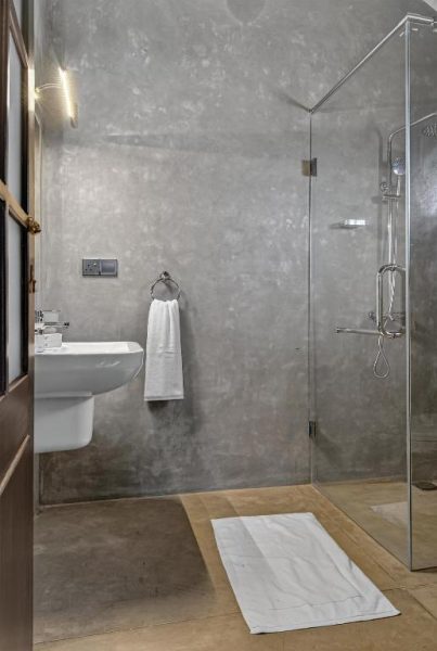 Baño moderno con ducha de cristal y paredes de microcemento gris en The Tusker's Hideout