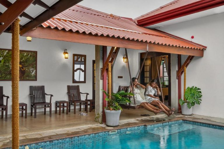 Dos mujeres en columpio junto a la piscina privada con terraza cubierta en The Tusker's Hideout