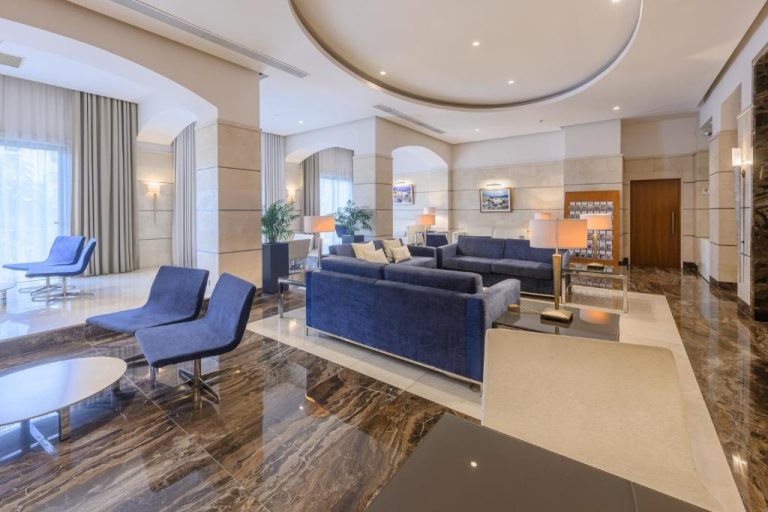 Elegante lobby del Maritim Antonine Hotel & Spa con sofás azules y suelo de mármol